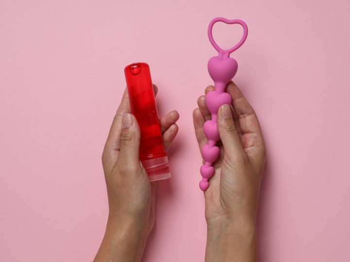Lubricant,With,Anal,Balls,In,Hands,On,Pink,Background
