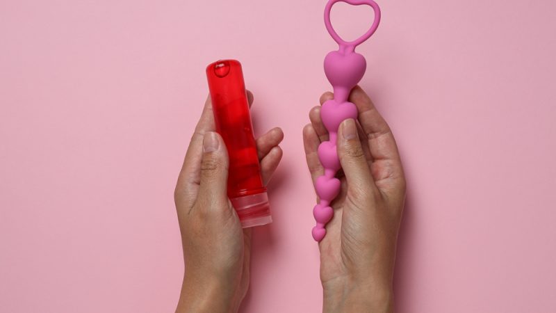 Lubricant,With,Anal,Balls,In,Hands,On,Pink,Background